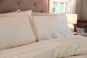 Organic cotton pillow shams with pillows on a made bed in natural color.