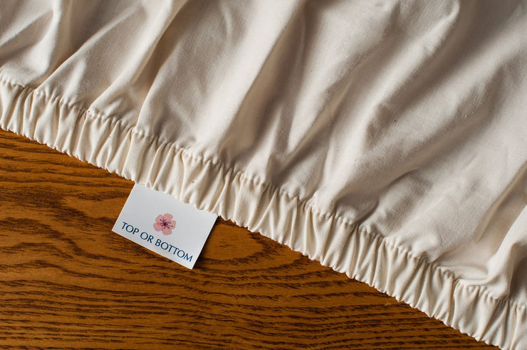 Organic cotton crib sheets in natural color showing american blossom linens tag.