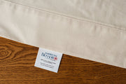 Flat organic cotton sheet in natural color displaying american blossom linens tag.