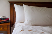 Organic cotton pillowcases in natural color on a bed.