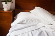 Unmade bed with organic cotton sheets in white color.